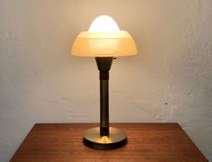 a lamp that is sitting on top of a wooden table next to a white wall