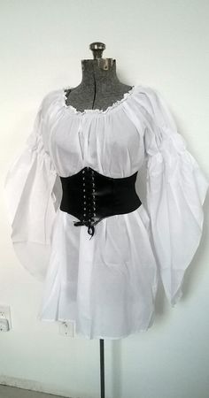 "UNIQUE CUSTOM STYLE, STAND OUT FROM THE CROWD! Versatile Chemise for all Your Costume Needs On or Off shoulders 100% Cotton 32\" Long Chemise Elastic neckline, On or Off Shoulder Long Flowing Sleeves with 2 Elastic Puffs, On Or Off Shoulder *SUPER VERSATILE* YOU'LL LOVE THIS CHEMISE FOR ALL YOUR RENAISSANCE, PIRATE, STEAMPUNK, WENCH, PEASANT OR MERCHANT COSTUMES. PERFECT FOR FAIRES, PLAYS, CIVIL WAR REENACTMENTS, EDWARDIAN, VICTORIAN & BOHO FESTIVALS AND MUCH MORE! SIZES Regular US Women's Pirate Blouses, Fair Fits, White Chemise, Pirate Dress, Victorian Boho, Flowing Sleeves, Pirate Outfit, Fair Outfits, Pirate Wench