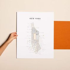 a person holding up a new york city map on top of a piece of paper