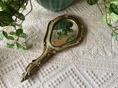 a mirror sitting on top of a table next to a potted plant and some leaves