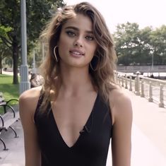 a beautiful young woman standing in front of a park bench with her hands on her hips