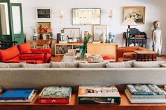 a living room filled with lots of furniture and books on top of a wooden table