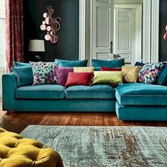 a living room with blue couches and colorful pillows on the sofa, along with rugs