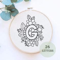 the letter g is surrounded by flowers and leaves on a white background with text below it