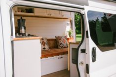 the interior of a camper van with its door open and pillows on the bench