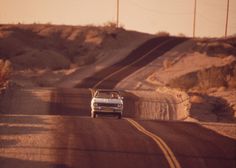 a white car driving down a dirt road