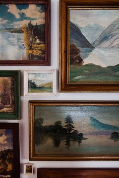 many paintings are hanging on the wall near each other