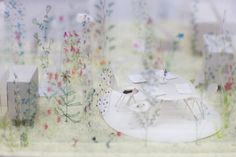 a miniature table and chairs are in the middle of a flowery field with flowers