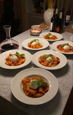 several plates of food on a table with wine and bottles in the backround