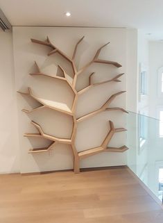 a large wooden tree sculpture in the corner of a room with hardwood floors and white walls