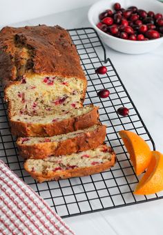 a loaf of cranberry bread sitting on top of a cooling rack next to an orange slice