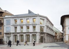 people are walking around in front of a white building with many windows and balconies