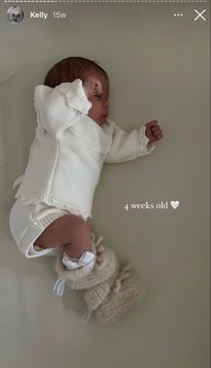 a baby is laying on its back in a white outfit