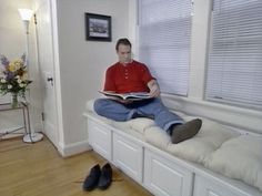 a man sitting on a window sill reading a book while wearing slip - ons