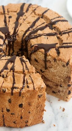 a cake with chocolate frosting on top sitting on a marble table next to a plate