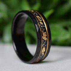 a black and gold wedding ring sitting on top of a table