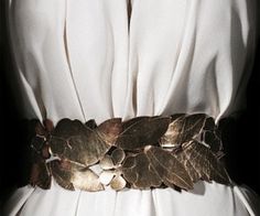 a woman wearing a white dress with leaves on her belt