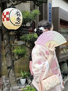 a woman in a kimono is holding a fan