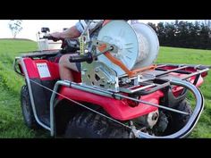 a man riding on the back of a red four wheeler with a reel attached to it