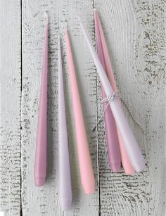 three pink and white candles sitting next to each other on top of a wooden table