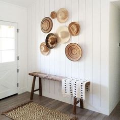 a white room with plates on the wall and a wooden bench in front of it