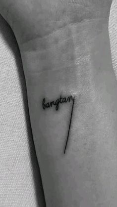 a small tattoo on the wrist that says bangtan'in cursive writing