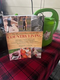 a book sitting on top of a table next to a green watering can and potted plant