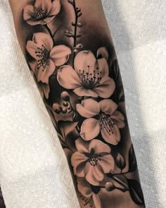 a black and white tattoo with flowers on the arm, done by an expert in body art