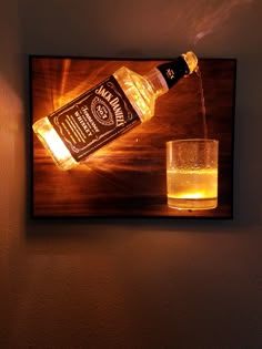 a bottle of whiskey is being poured into a glass on a wooden table with a lit light behind it