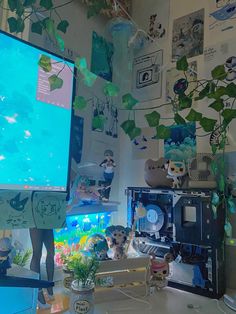 a computer monitor sitting on top of a desk in front of a fish tank filled with plants