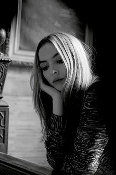 a black and white photo of a woman leaning on a table