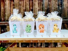 three small plastic containers filled with popcorn sitting on top of a table next to a wooden fence