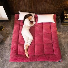 a woman laying on top of a red bed