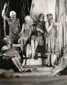 an old black and white photo of women dressed in costume sitting on stage with balloons