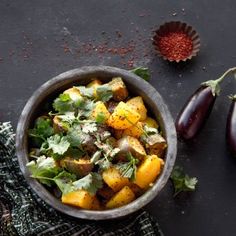 a bowl filled with food next to an eggplant and other vegetables on a table