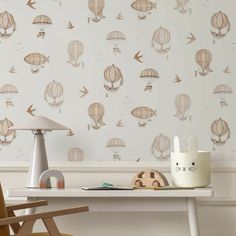 a desk with a lamp, chair and wallpaper that has hot air balloons on it