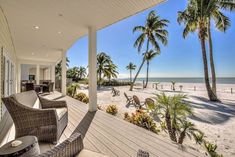 a porch with chairs and palm trees on the beach