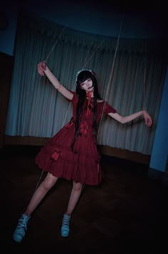 a woman in a red dress is holding strings