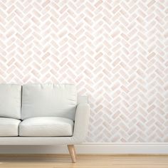 a white couch sitting in front of a wall with a pink geometric pattern on it