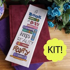 a cross - stitch bookmark with the words bookshelf on it next to some flowers