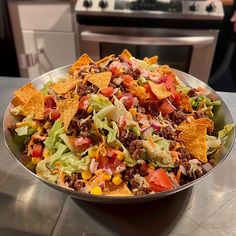 a large bowl filled with taco salad and tortilla chips on top of a counter