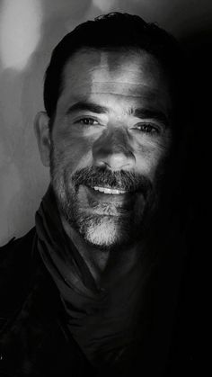 a black and white photo of a man with a goatee smiling at the camera