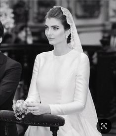 a black and white photo of a woman in a wedding dress sitting on a chair