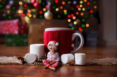 a small child sitting on the floor next to a coffee cup and marshmallows