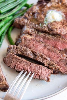 steak and green beans on a plate with a fork in the middle, ready to be eaten