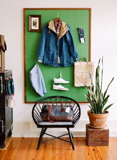 a coat rack with clothes hanging on it and a chair in front of it next to a potted plant