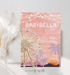 a pink and gold baby shower party with a ferris wheel on the front, palm trees in the background