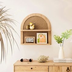 a wooden table topped with a white vase filled with flowers and plants next to a wall mounted clock