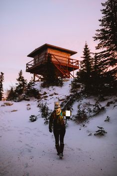 a person walking in the snow towards a cabin