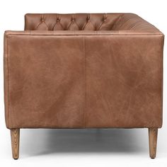 a brown leather couch sitting on top of a wooden frame